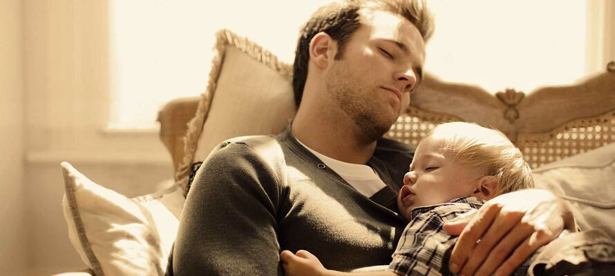 Schlafender Mann mit schlafendem Kind auf dem Arm.