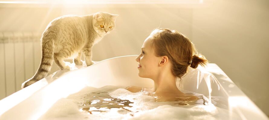 Frau liegt in der Badewanne und die Katze steht am Rand.
