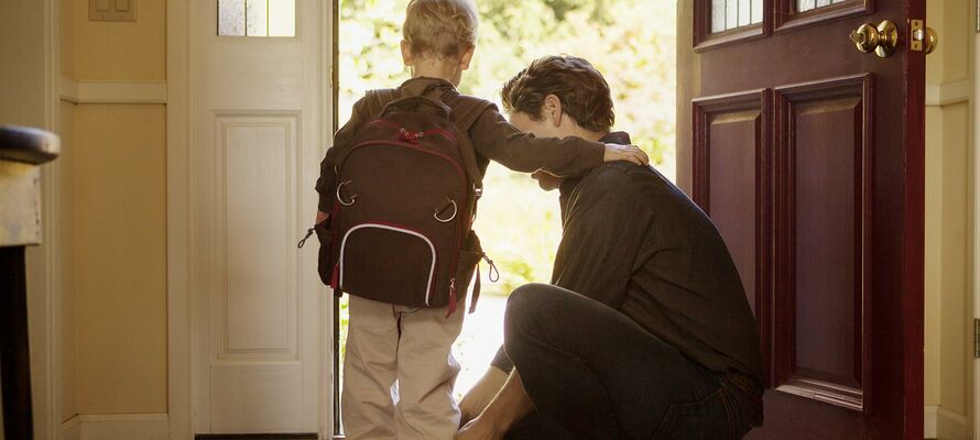 Kind beim Verlassen des Hauses und Vater bindet ihm die Schuhe.